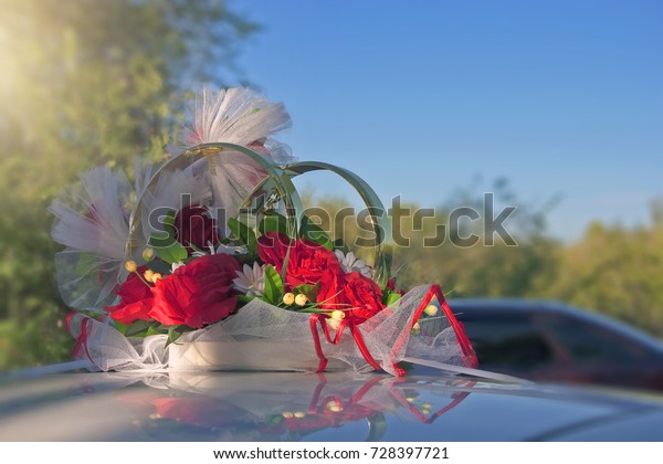 closeup of decorations on a\
wedding car for the bride and groom, wedding rings on top of the\
car