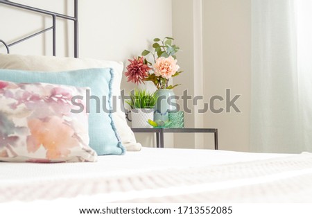 Closeup of a decorative bedside table with artificial flowers in a bright bedroom. Bright minimalist decor. Interior design. Inspirational ideas.