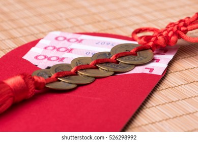 Close-up of decorative Chinese lucky coins and lucky money in red envelope on bamboo mat, selective focus