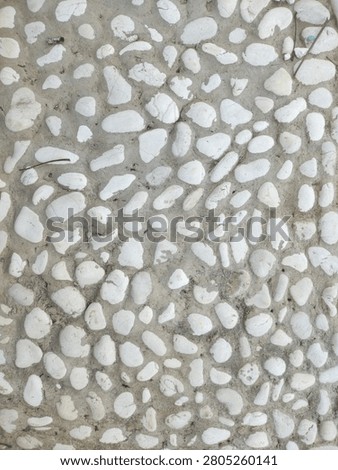 Close-up of a decorative pebbled concrete surface, providing a natural texture. Versatile background with ample copy space for impactful advertising and compelling news content.