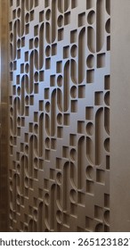 A close-up of a decorative wall panel with a repeating, modern geometric pattern of interlocking curves and squares.