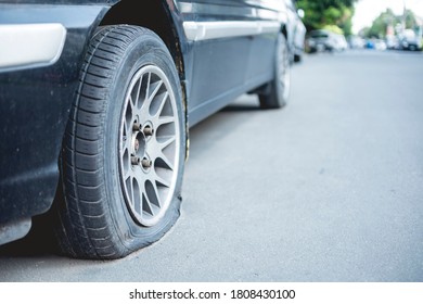 Closeup of a deflated or flat tire that has been neglected for days. Of an automobile parked along a street.