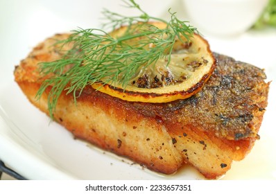 Closeup of delectable pan seared sea bass with lemon slice and dill - Shutterstock ID 2233657351