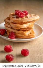 Close-up of a delectable stack of heart-shaped waffles, generously adorned with fresh red raspberries and a sprinkle of powdered sugar on wooden table