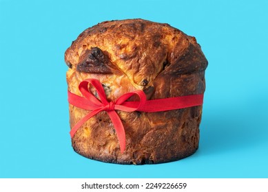 Close-up with a delicious homemade panettone, minimalist on a blue background. Panettone with red bow tie, isolated on a blue background - Powered by Shutterstock