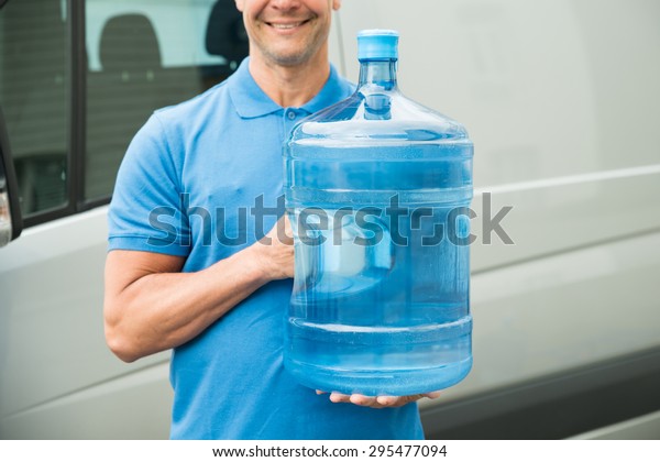Close-up Of Delivery Man In Blue Uniform Carrying\
Large Water Bottle