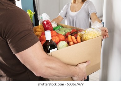 Close-up Of A Delivery Man Giving Grocery Cardboard Box To Woman