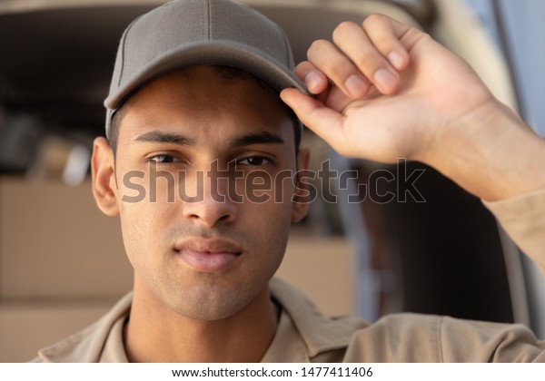 Close-up of\
delivery man looking at camera near van outside the warehouse. This\
is a freight transportation and distribution warehouse. Industrial\
and industrial workers\
concept