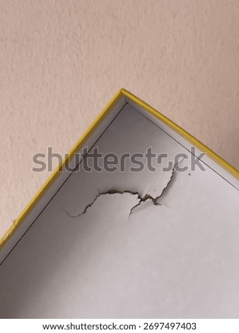 Close-up of a dented and torn puzzle box, illustrating poor parcel handling and delivery damage on cardboard packaging.