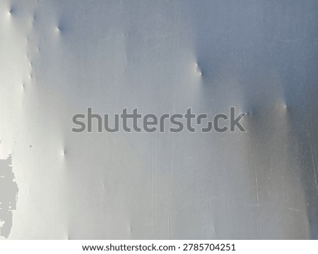 Close-up of a dented or warped light-colored surface with multiple small bumps and a prominent puncture or deep indentation.