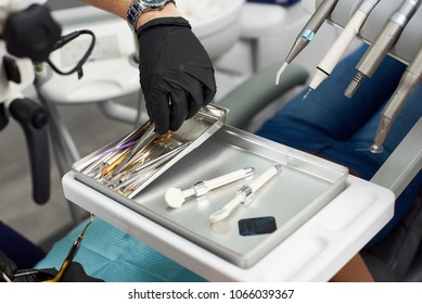 Close-up of a dentist in a black glove takes a tool to treat the patient. The concept of modern dentistry