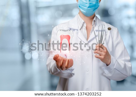 A closeup of dentist holding image of digital tooth model with roots and set of dental medicine tools at blurred hospital room background. The concept of innovative dental treatment and diagnostics.