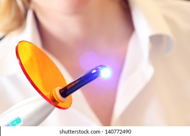 Close-up Of A Dentist Holding A Lit Dental Curing UV Light