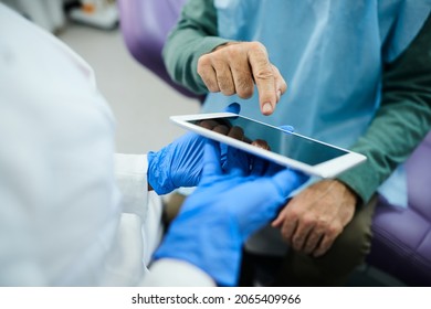 Close-up Of Dentist And Senior Patient Using Touchpad During Dental Appointment.