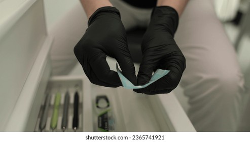 Close-up of dentist's hands holding dental tools and toothpaste. The use of sterile materials and the process of professional teeth cleaning in a dental clinic. - Shutterstock ID 2365741921