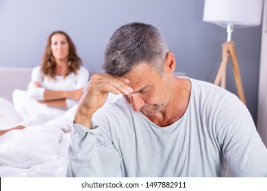 Close-up Of Depressed Man Sitting On Bed In Front Of Her Wife At Home - Powered by Shutterstock