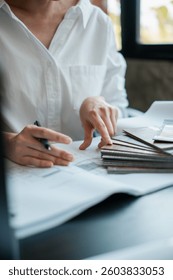 Close-up of a designer examining material samples and blueprints, highlighting creativity and attention to detail.