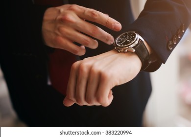 closeup designer watch on businessman hand, he looks on the time and hurrying