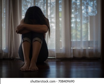 Closeup despaired woman hug her knee and cry while sitting alone on the floor. - Shutterstock ID 708409690