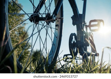 Close-up detail of a bicycle parked in a meadow, against the backdrop of the sun and blue sky, on a summer day. Healthy and active lifestyle concept. Bottom view.