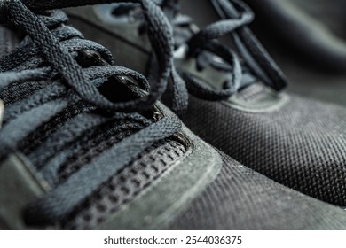 Close-up detail of black athletic shoes showcasing lace texture and fabric design in a soft background setting - Powered by Shutterstock