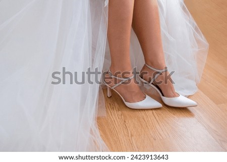 Closeup detail of bride putting on high heeled sandal wedding shoes.