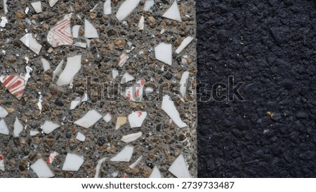 Close-up detail of a cement wall surface embedded with white glass fragments, creating a unique textured pattern and reflective highlights. The abstract composition is ideal for design backgrounds, architectural details, and modern surface concepts, emphasizing rough texture, contrast, and material aesthetics.