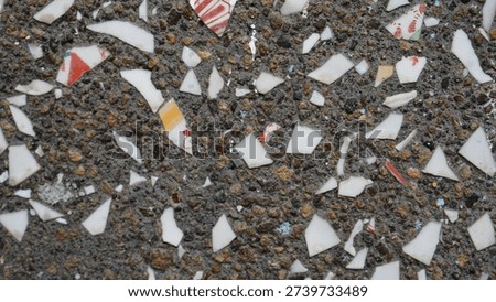 Close-up detail of a cement wall surface embedded with white glass fragments, creating a unique textured pattern and reflective highlights. The abstract composition is ideal for design backgrounds, architectural details, and modern surface concepts, emphasizing rough texture, contrast, and material aesthetics.