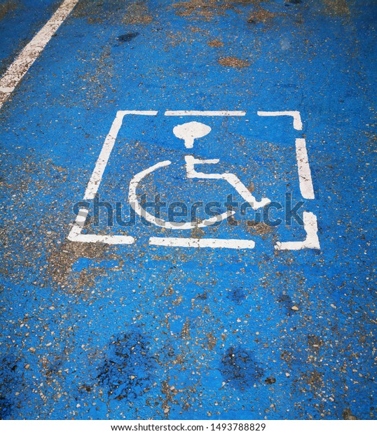 closeup detail of\
disabled parking permitted zone in vivid blue showing signs of\
weathering and hard use
