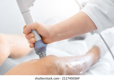 Closeup detail doctor medician hand do extracorporeal shock wave ultrasound knee eswt treatment procedure for senior patient at medical office. Physiotherapy rehabilitation and treatment. Healthcare