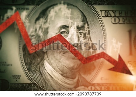 Closeup detail of  dollar bill.  Economist forecast for the United States. Glowing red arrow going downwards on Benjamin Franklin portrait on dollar bill.  Effect of recession on US economy.