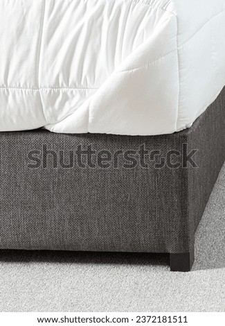 Close-up Detail of Down Comforter, White Mattress Protector on Gray Low Fabric Platform Bed in Bedroom, Over a Gray Area Rug.