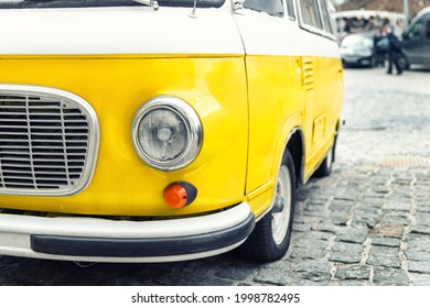 Close-up detail front view of headlight part old vintage bright yellow retro mini bus car van parked in european city center on cobble stone paved road. Fun vehicle for snack delivery sale journey - Powered by Shutterstock