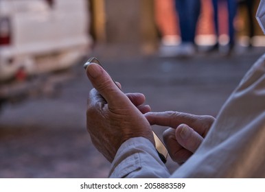 Close-up Detail Of The Hand Of An Elderly Man Using His Mobile Phone On The Street. Concept Use Of Technology By The Elderly. Older Man Using Technology. Selective Focused