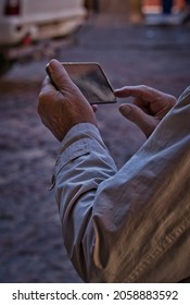 Close-up Detail Of The Hand Of An Elderly Man Using His Mobile Phone On The Street. Concept Use Of Technology By The Elderly. Older Man Using Technology. Selective Focused