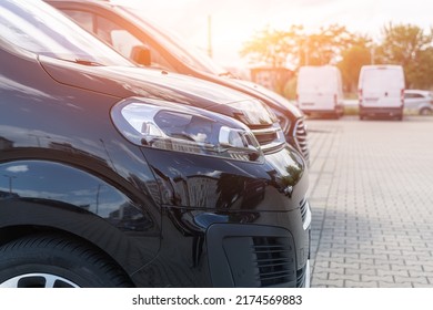 Close-up Detail Headlight View Of Many Modern Luxury Black Vans Parked In Row At Car Sale Rental Leasing Dealer Against Sunset. Commericial Trasfer Cargo Transportation Company Fleet. Vip Charter