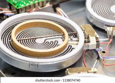 Close-up Detail Heating Coil Spiral Of Diassembled Cooking Stove Cooktop. Repair And Maintenance Of House Kitchen Appliance At Electric Fixing Workshop.