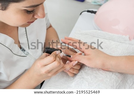 close-up detail of the manicurist girl applying a nail polish on the nails to strengthen and firm the keratin. woman preparing the nails to start applying the gel and acrylic. polygel technique