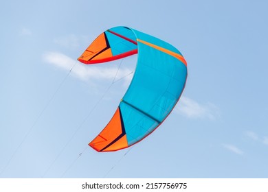 Close-up detail one bright blue orange kitesurf wings kite equipment fly against clear sky t on bright sunny day against at kiter riding surf school camp. Active travel sport concept