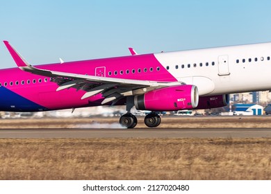 Close-up Detail Scenic View Of Big Modern Passenger Plane Landing On Tarmac Airport Runway Against Blue Clear Sky On Sunny Day. Close Of Aircraft Chassis Wheels Mak Smoke At Ground Touchdown Moment.