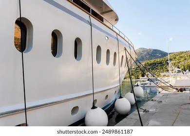 Close-up detail side view big luxury cruise yacht boat moored at Croatian bay harbor moored at jetty dock plastic fenders by bright summer sunny sunset sunrise morning.  Boat vessel charter service - Powered by Shutterstock