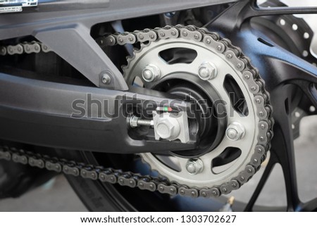 Closeup detail of sport racing motorcycle wheel and swingarm with rear drive o-ring chain and sprocket power transmission from the engine to wheel.