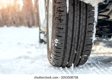 Close-up detail view of car wheel with unsafe summer tread tire during driving through slippery snow road at winter season. Danger traffic accident collision risk. Seasonal tyre switch concept