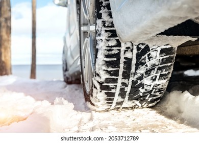 Close-up detail view of car wheel with winter tread tire during driving through slippery snow snowdrift country dirt road at cold season. Danger traffic accident risk. Seasonal tyre switch concept
