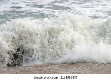 Close-up Detail Of White Spray Of A Large Ocean Wave Breaking In The Shallows Onto Beach Sand. No People.