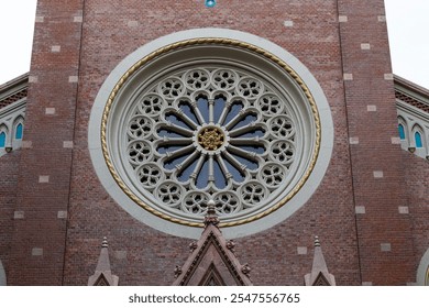 Close-up of a detailed rose window on a historic brick church facade, showcasing intricate architecture. - Powered by Shutterstock