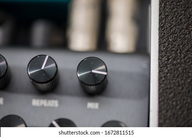 Close-up details of control knobs on the top of a hardware effects pedal made for guitars, synthesizers, and other musical instruments.
