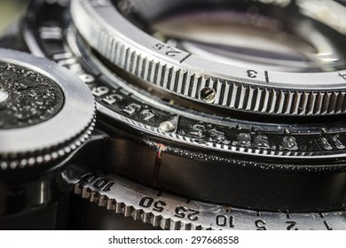 close-up details of an old silver metallic lens camera with a distance ring, shutter speed and aperture