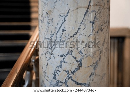 Closeup details on marble pillar with marble stairways in background.