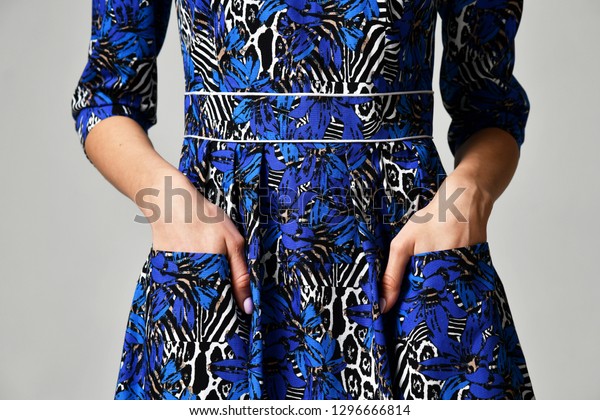 Closeup details of woman blue dress pocket on\
grey background
